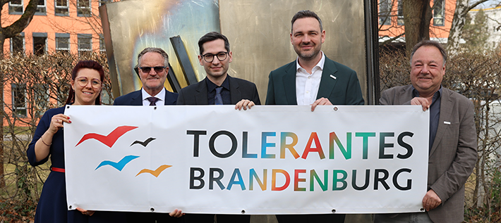 Karina Berg (HVD-BB, Landeskoordination Brandenburg), Dr. Bruno Osuch (HVD-BB, Politische Kommunikation), Staatssekretär David Kolesnyk, David Driese (HVD-BB, Vorstand) und Alfred Roos (Referatsleiter Koordinierungsstelle „Tolerantes Brandenburg“) halten gemeinsam ein Banner mit dem Logo "Tolerantes Brandenburg"