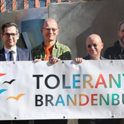 Annedore Althausen (ADFC), Staatssekretär David Kolesnyk, Christian Wessel (ADFC), Frank Stieldorf und Hilmar Hilger (beide von der Rheinsberger Preussenquelle) sowie Alfred Roos, Referatsleiter Koordinierungsstelle „Tolerantes Brandenburg“ halten das Logo der Koordinierungsstelle hoch